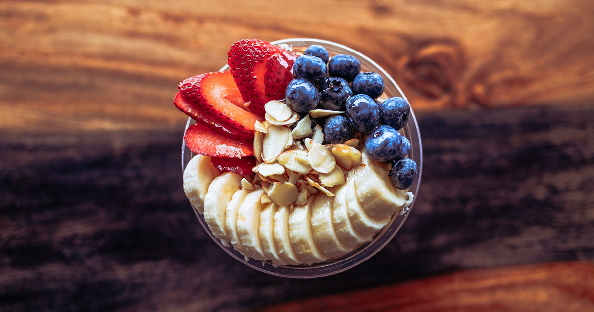 Smoothie bowl topped with banana, strawberries, blueberries, and almonds.